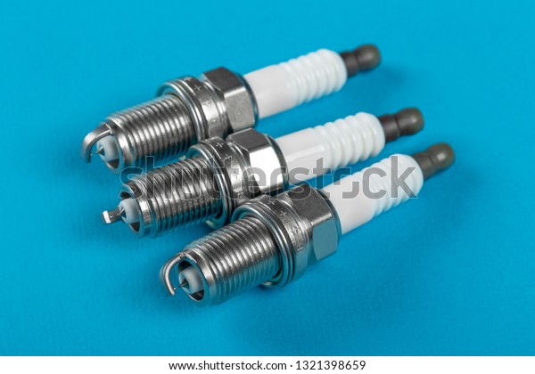 A set of new\
spark plugs a blue background. Studio macro image of high quality.\
To advertise auto service.