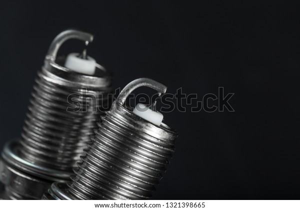A set of new spark plugs of the\
car, and spare parts of vehicles on a dark red background. Studio\
macro image of high quality. To advertise auto\
service.
