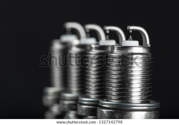 A set of new spark plugs of the car, and\
spare parts of vehicles on a dark  background. Studio macro image\
of high quality. To advertise auto\
service.