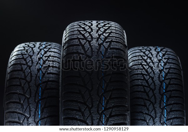 Set of new\
winter tires on black background with contrasty lighting. Close up\
product photograph of unused\
tyres