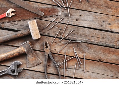 Set of old hand tools for repair, top view. Hand tools on a plank floor. Old hand tools on a wooden surface. Sledgehammer, axe, saw, pliers, adjustable wrench, file and nails. Everything for repair - Powered by Shutterstock