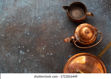 Set Of Old Vintage Copper Empty Tableware On Rustic Concrete Background. Antique Copper Utensils: Pan, Teapot, Sauce Boat. Top View Of Beautiful Aged Retro Brass Cookware From Flea Market, Copy Space