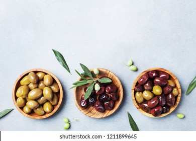 Set from olives in wooden bowls decorated with fresh olive tree branch top view. - Powered by Shutterstock