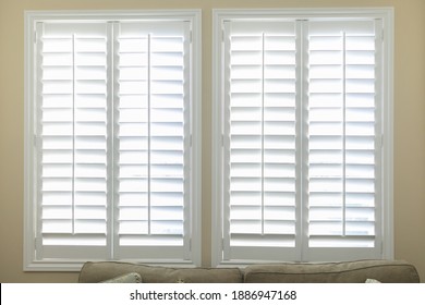 A set of open white plantation shutters in a light butter yelllow room