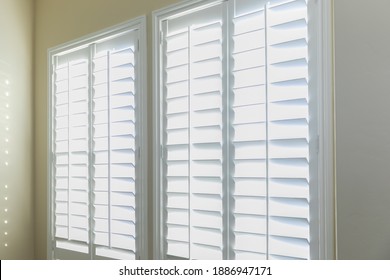 A set of open white plantation shutters in a light butter yelllow room