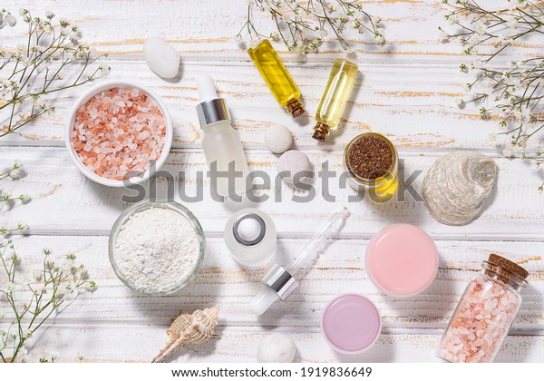 Set of\
organic skin care cosmetic and beautiful flowers on white rustic\
background top view. Spa and wellness\
concept.