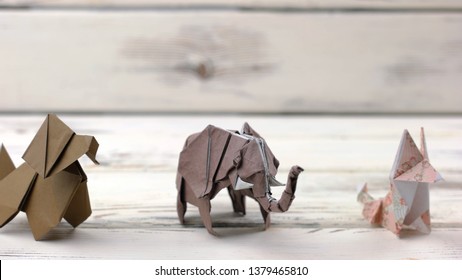 Set of origami animals on wooden background. Collection of paper animal models on white wooden table. Exhibition of japanese paper art.