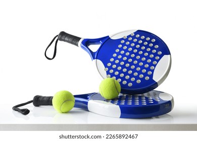 Set of paddle tennis rackets and balls the reflected on white table and white isolated background. Front view. - Powered by Shutterstock