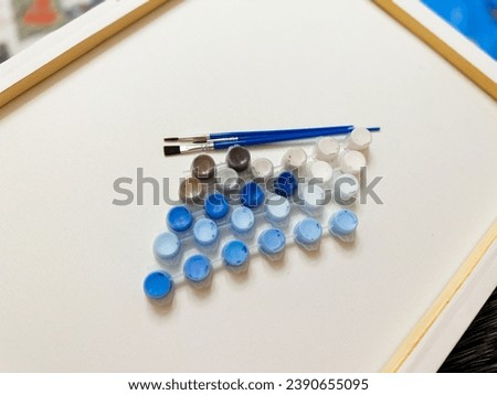 a set for painting on canvas of blue shades, paints in small boxes with blue brushes made of natural bristles. artistic concept