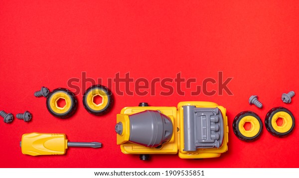 A set of parts and tools to collect the\
designer of the truck mixer machine on a red with copyspace for\
text. The screwdriver and cogs of the machine, which can be\
disassembled and assembled.