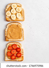 Set of peanut butter open sandwiches or toasts (toasted bread, peanut butter, banana and fresh strawberry slices). Healthy morning breakfast. Top view food. Copy space. White concrete background.
