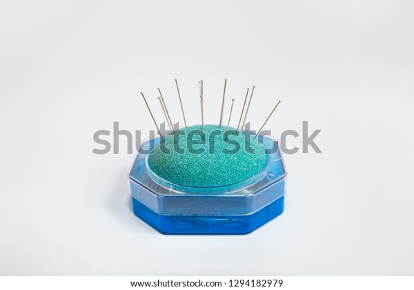 Set of pin cushion in box with sewing pins\
isolated on white\
background.