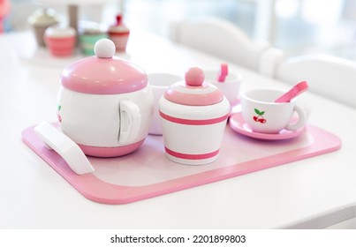 A set of pink white pastel color wood  toy tea cups including 2 coffee cups with teaspoons, a teapot, a sugar jar  and a milk jug is placed on a tray. - Powered by Shutterstock