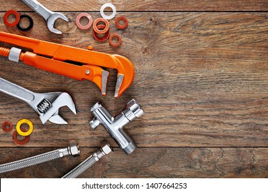 Set Of Plumbing Tools On Wooden Table Background. Close Up Top Down View With Copy Space.