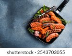 A set of pork, beef and chicken sausages in a metal grill pan. Top view, free space for text.