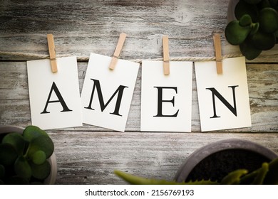 A set of printed cards spelling the word AMEN on an aged wooden background.