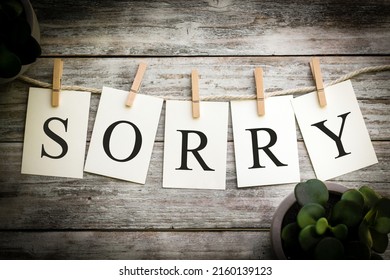 A set of printed cards spelling the word SORRY on an aged wooden background.