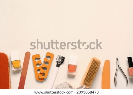 Set of professional tools for pedicure with nail polishes on beige background