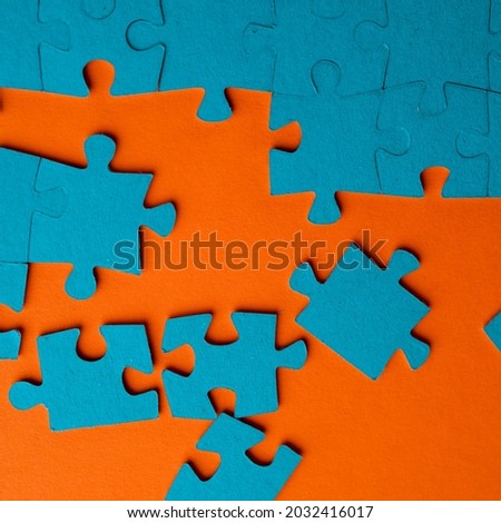 A set of puzzles, the process of collecting in a large pattern. Teamwork and problem solving, concept. Blue mosaic on orange
