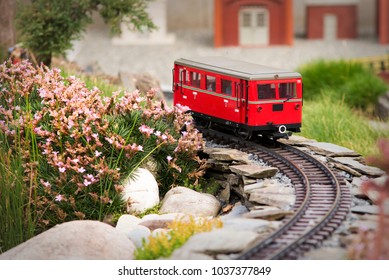 Set Of Red Electric Model Railway Locomotive And Layout With A Station And Whole Scene With Features.