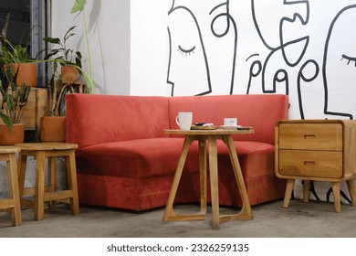 A set a red sofa, wooden stools, a table, and a side table with some plants as decoration - Shutterstock ID 2326259135