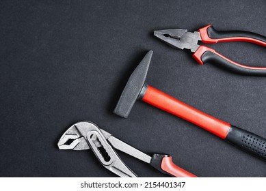 Set Of Renovation Tools. Instruments For Repair And Maintenance. Hammer, Wrench And Tongs On Black Background, Top View Flat Lay