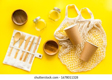 Set Of Reusable Items For Eco-friendly Lifestyle. Cotton Bag, Glass Jars, Wooden Tableware. Zero Waste, Organic Shopping Concept. Yellow Background, Top Down