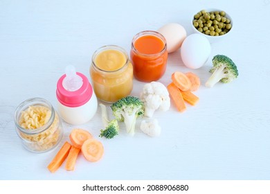 A Set Of The Right Foods For A Child's Nutrition. Complementary Feeding Of Canned Puree And Pieces. Vegetables, Carrots, Cabbage, Broccoli, Eggs, Pasta, Cereal Cookies, Infant Formula In A Bottle.