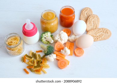 A Set Of The Right Foods For A Child's Nutrition. Complementary Feeding Of Canned Puree And Pieces. Vegetables, Carrots, Cabbage, Broccoli, Eggs, Pasta, Cereal Cookies, Baby Formula In A Bottle