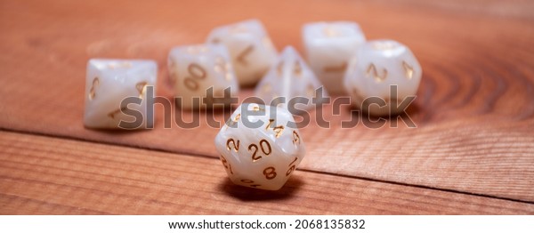Set of role\
playing white dices on a gaming table made of wood: banner for\
Dungeons and Dragons role-playing\
games