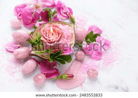 set of Rose quartz crystals tools. yoni eggs, gua sha stone, flower candle, sea salt, wild rose flowers on marble background. Healing Crystals For Body Care, Relationship, Self care. meditation ritual