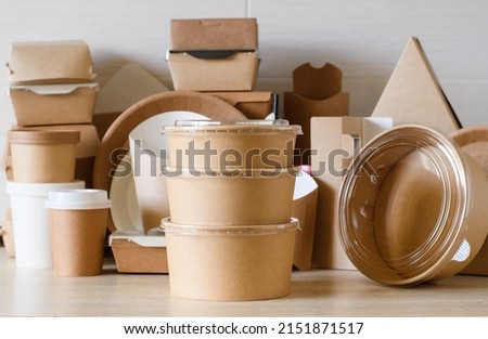 A set of round paper containers for food on the background of paper utensils and packaging. The concept of using dishes and packaging made from biodegradable environmentally friendly materials.
