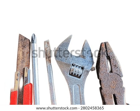 A set of rusty old hand tools including a cutter, screwdrivers, adjustable wrench, and pliers isolated on a white background.