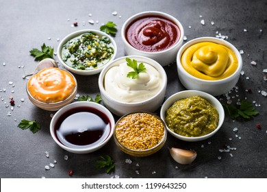 Set of sauces - ketchup, mayonnaise, mustard soy sauce, bbq sauce, pesto, chimichurri, mustard grains and pomegranate sauce on dark stone background. - Shutterstock ID 1199643250