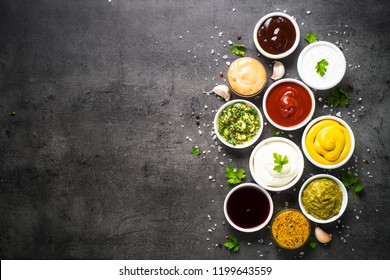 Set Of Sauces - Ketchup, Mayonnaise, Mustard Soy Sauce, Bbq Sauce, Pesto, Chimichurri, Mustard Grains And Pomegranate Sauce On Dark Stone Background. Top View Copy Space.