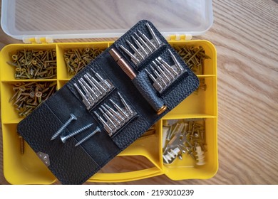 Set Of Screwdrivers With Nozzles And A Plastic Box With Different Screws And Screws Lie On A Wooden Table. View From Above