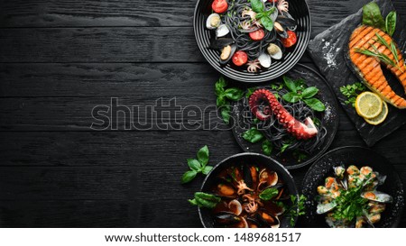 Set of Seafood Dishes. Seafood on a plate. On a black wooden background. Top view. Free copy space.
