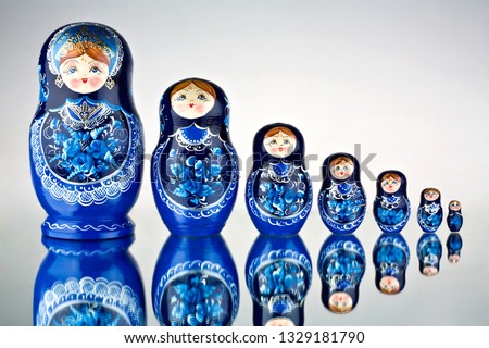A set of seven blue painted Russian nesting dolls on mirror surface. Creative concept photo of set of seven blue painted national toys Russian nesting dolls on mirror surface.