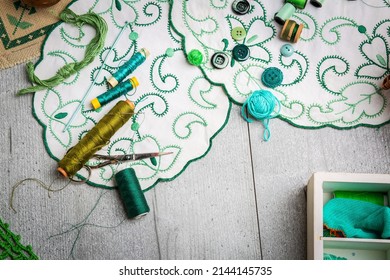Set of sewing and embroidery supplies on a table: sewing thread, buttons, crochet, embroidered doiles, scissors