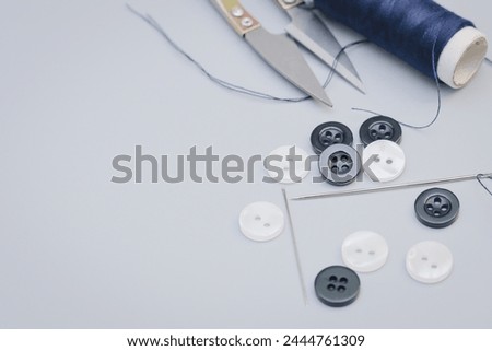 Set of sewing threads, buttons and needles on gray background, in right angle and flat. With space for text on the left