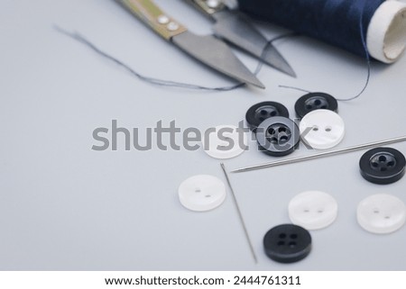 Set of sewing threads, buttons and needles on gray background, in right angle and flat. With space for text on the left