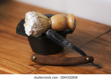 Set of shaving equipment and men's cosmetic products on wooden table, barbershop. shave concept with a straight razor, shaving brush and foam