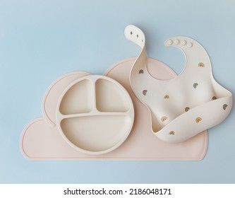 Set Of Silicone Dishware And Baby Accessories On Blue Light Background, Flat Lay