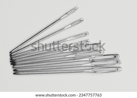 Set of silver sewing needles of different sizes isolated on white background top view, flat lay