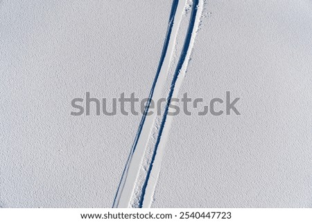A set of ski tracks forming a pattern in fresh, untouched off-piste snow, highlighting the thrill of off-trail skiing and winter exploration.