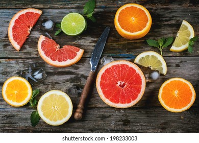 Set of sliced citrus fruits lemon, lime, orange, grapefruit with mint, ice and vintage knife over wooden background. Top view. - Powered by Shutterstock