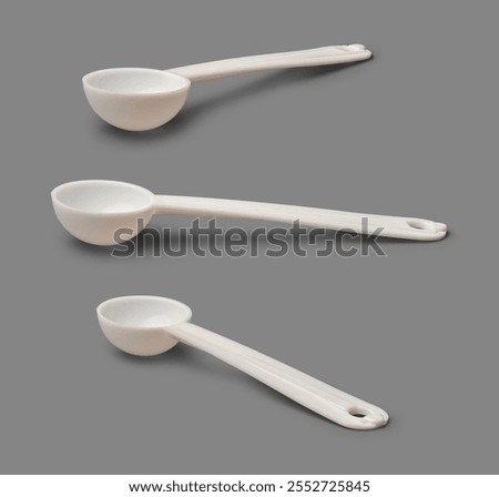 set of small plastic bowl shape spoons with long handle isolated gray background, food grade for measure powdered food, milk protein or supplements in different angles with shadows