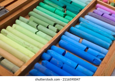 Set of soft pastels in wooden box as background, closeup. Drawing material