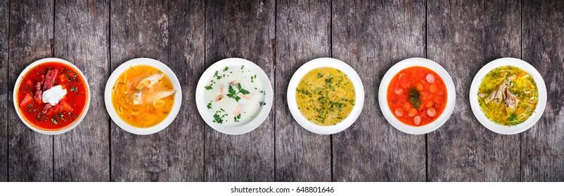 Set of soups from worldwide cuisines, healthy food. Cream soup with mushrooms, asian fish soup, soup with meat - solyanka, russian borscht, chicken soup on rustic wooden background. Top view