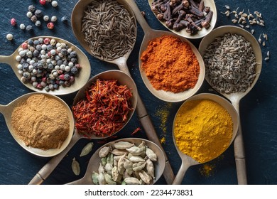 Set of spices in brass spoons, close up, top view. Various peppers, cardamom, carnation, turmeric, paprika and saffron for cooking - Powered by Shutterstock